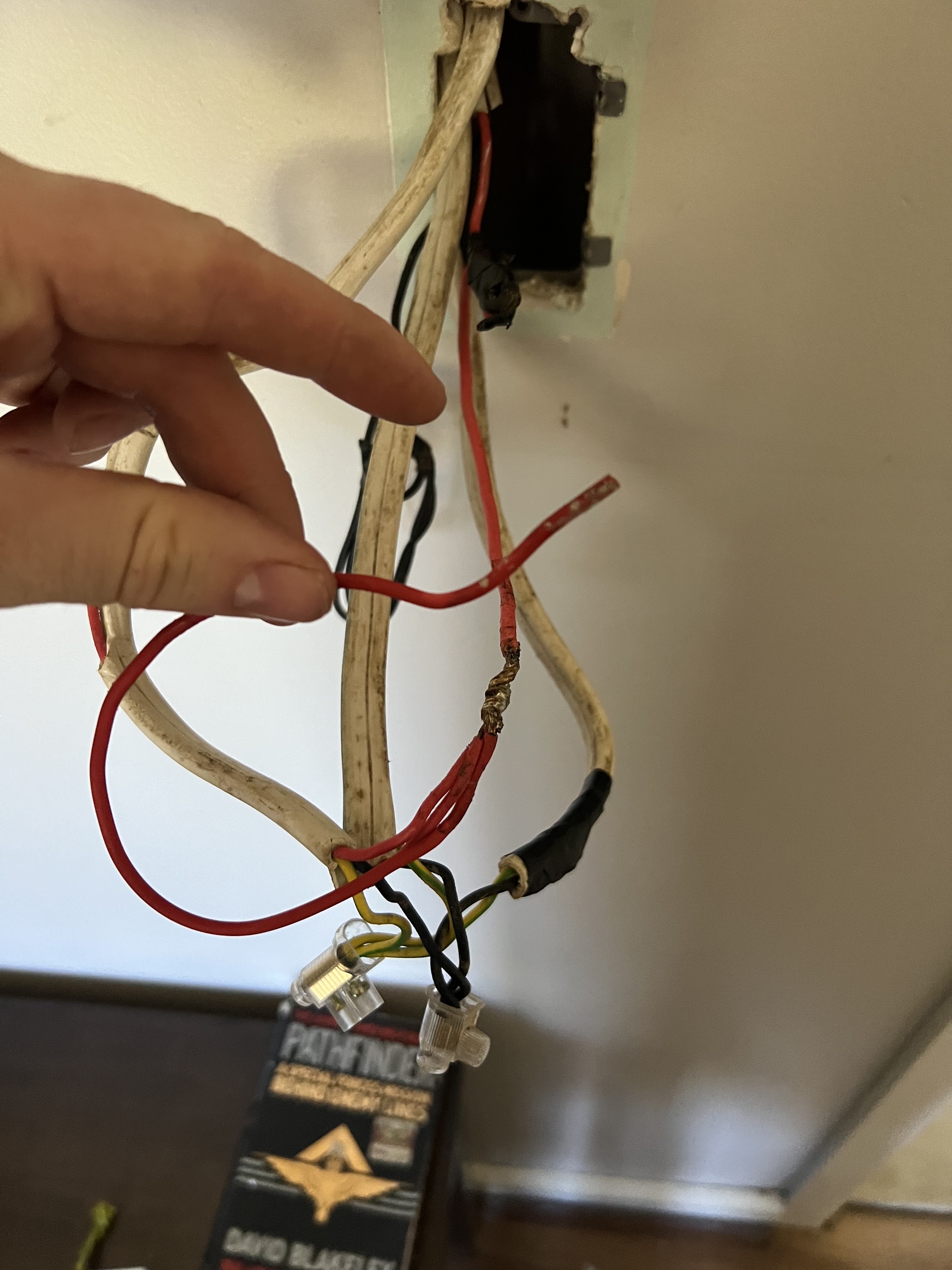 Hand holding old perished and burnt wiring taken out of a ceiling light point