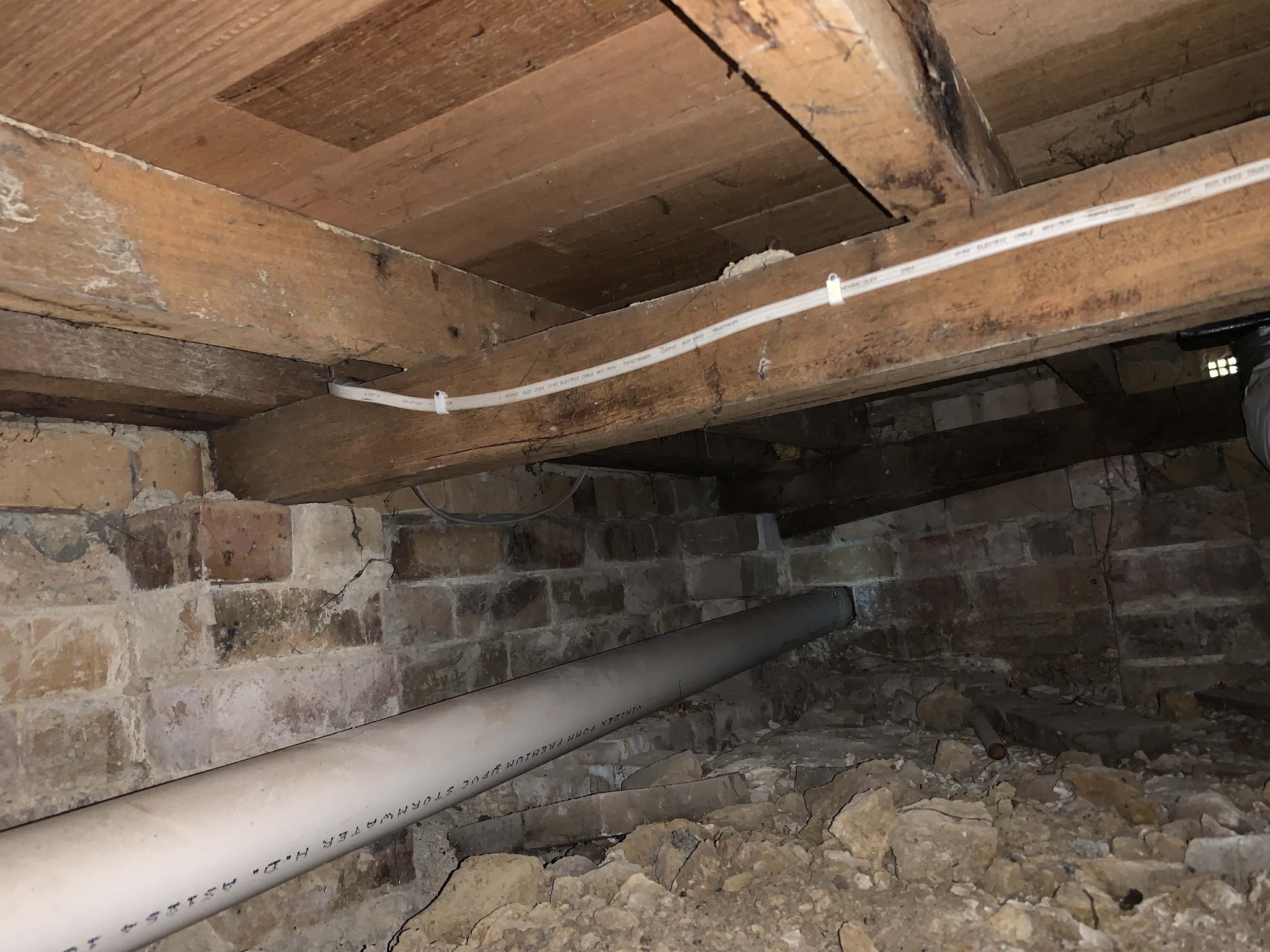New electrical cable clipped neatly along bearers in a brick pier subfloor